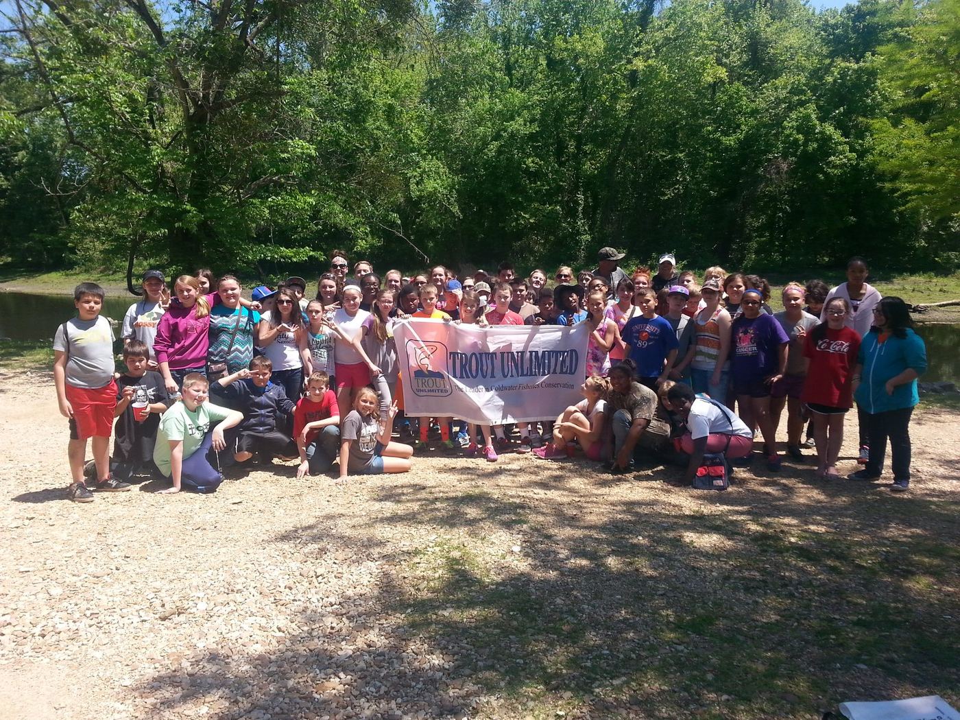 A class at the river with the Trout Unlimited banner