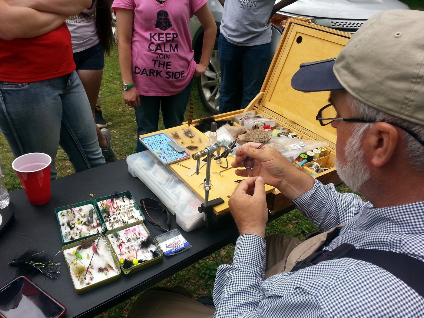 A volunteer tying a fly while students watch